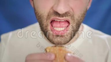 特写，一个留茬的男人吃汉堡.. 一只手拿着芝士汉堡。 它不会带来健康的生活方式